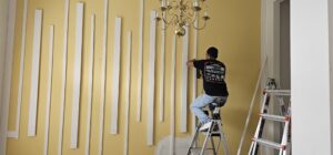 A skilled custom carpenter installing vertical wood slats on a feature wall, adding a modern and stylish touch to the home interior.