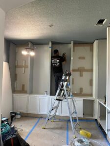 A custom carpenter from CFL Custom Carpentry working on the installation of built-in cabinets, ensuring precise craftsmanship and quality woodwork.