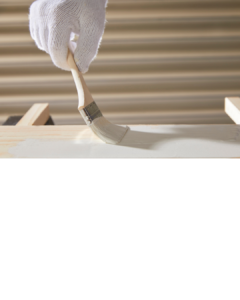 A gloved hand painting a wooden board with white paint, creating a smooth and even finish. At CFL Custom Carpentry, we specialize in achieving the best wood finishes for a flawless look.
