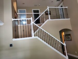 Sleek staircase design tips featuring black metal balusters and crisp white trim, designed and installed by CFL Custom Carpentry.