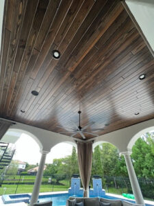 Custom outdoor patio ceiling with stained wood panels and recessed lighting, a perfect example from CFL Custom Carpentry that complements seasonal home maintenance tips for protecting exterior woodwork.