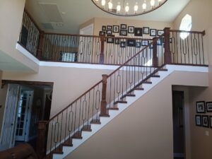 Traditional staircase design tips with ornamental wrought iron balusters and natural wood finishes by CFL Custom Carpentry.