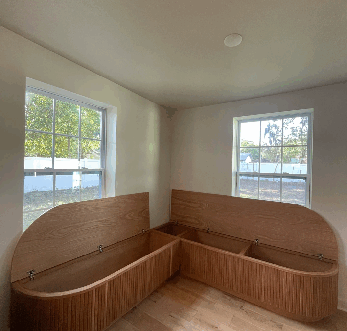 Custom curved corner bench with lift-up lids and internal storage compartments, showcasing elegant space-saving carpentry by CFL Custom Carpentry.